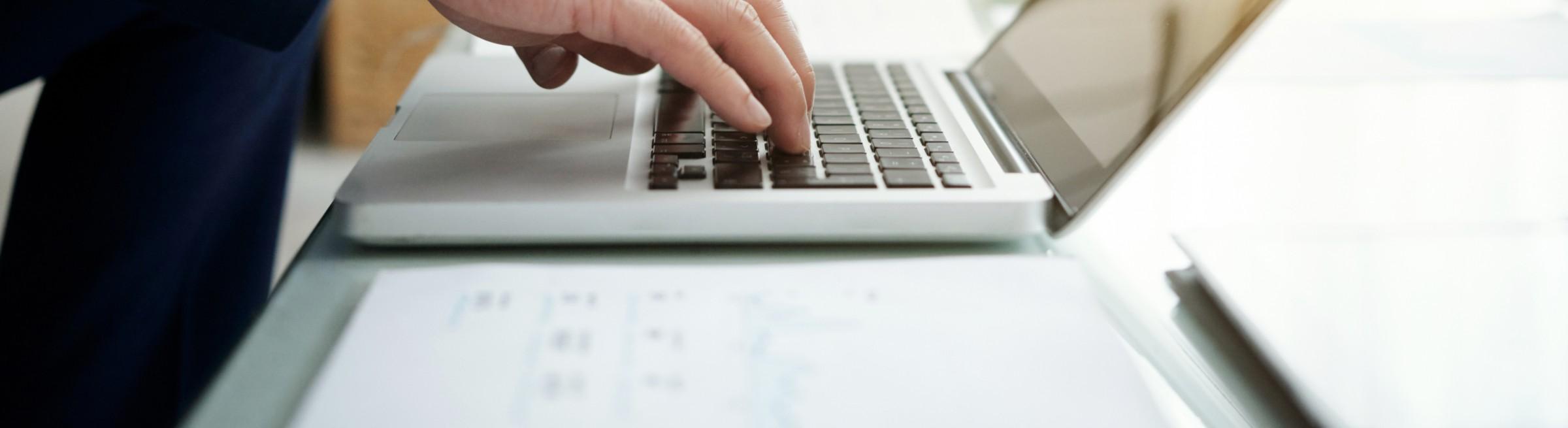 Un homme écrit sur son ordinateur portable